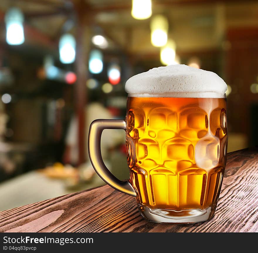 Glass of light beer on a dark pub.