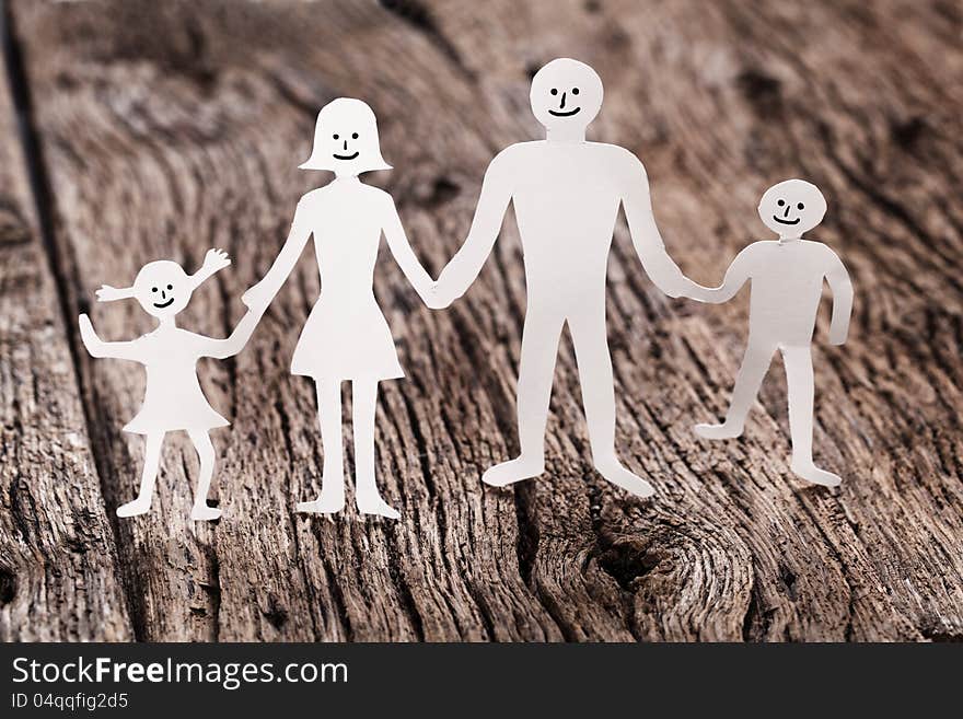 Cardboard figures of the family on a wooden table. The symbol of unity and happiness.