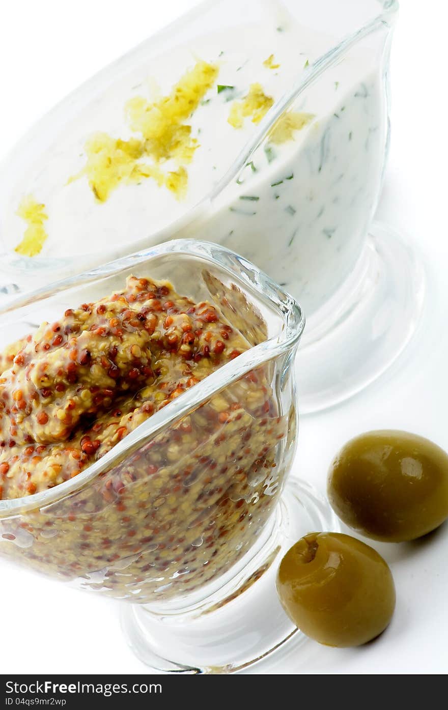 Whole Grain Mustard and Tartar Sauce with two Olives in Glass Gravy Boat on white background