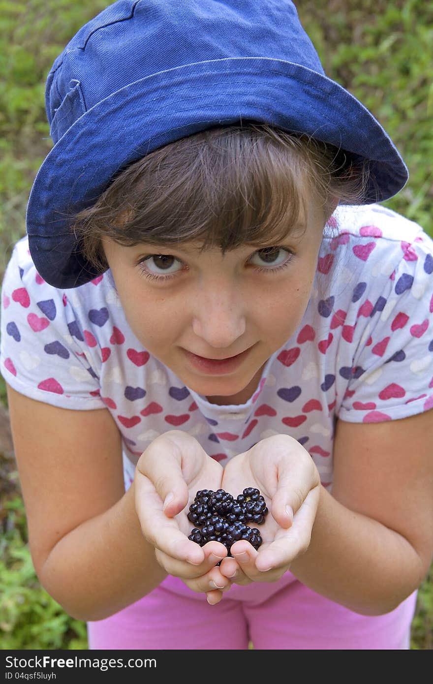 Cute girl showing blackberries in her hands