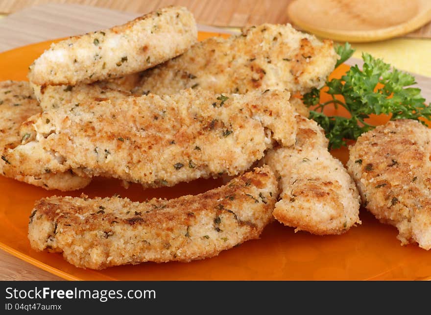 Chicken breast tenderloins on an orange platter