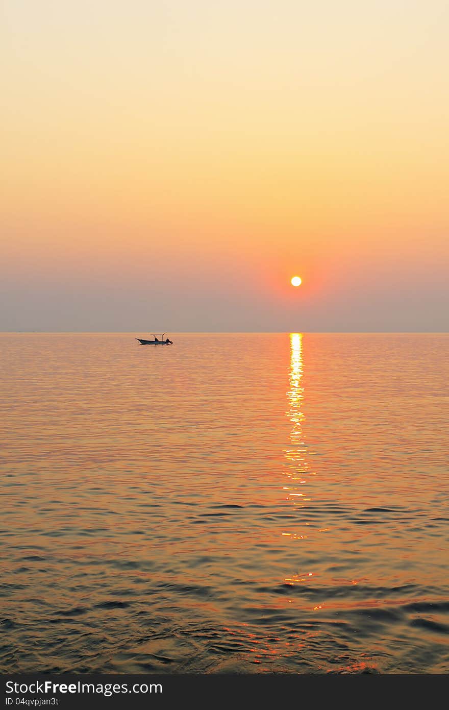 A small fishing boat in the sea at sunset.