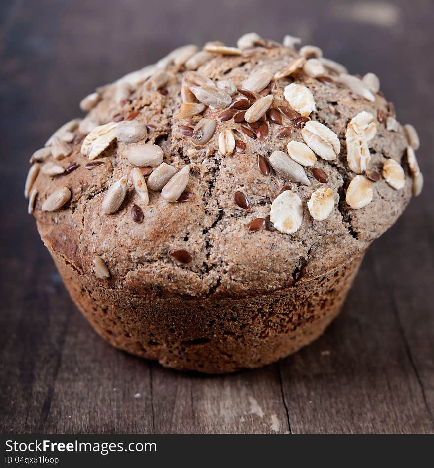 Close-up of blueberry muffin topped with oats and almonds on old plank. Close-up of blueberry muffin topped with oats and almonds on old plank