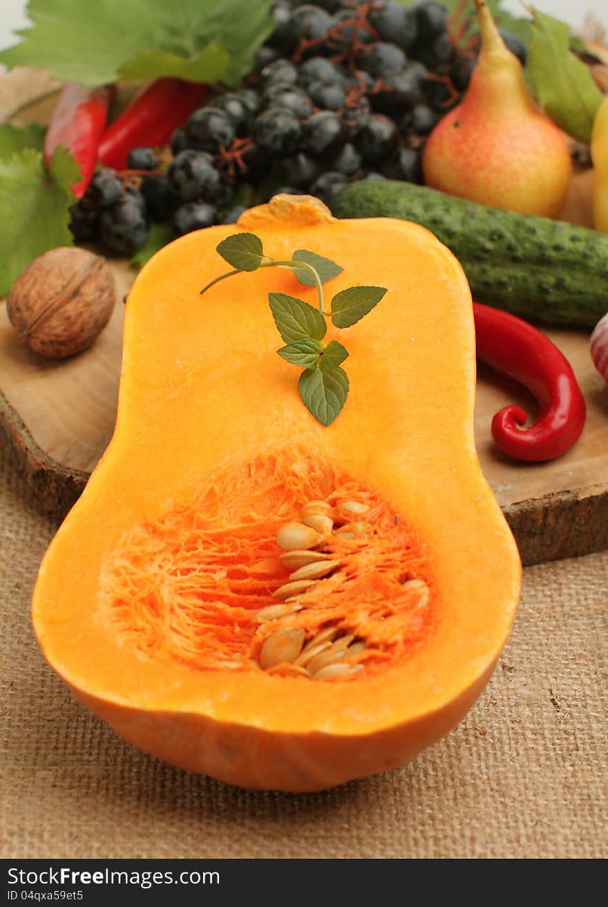 Half fresh pumpkin with other autumn fruits and vegetables