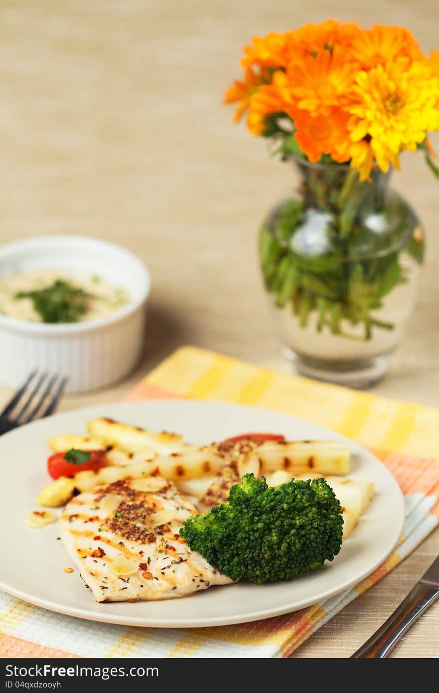 Grilled chicken breast with asparagus, broccoli, and spring tomatoes on white plate. Grilled chicken breast with asparagus, broccoli, and spring tomatoes on white plate