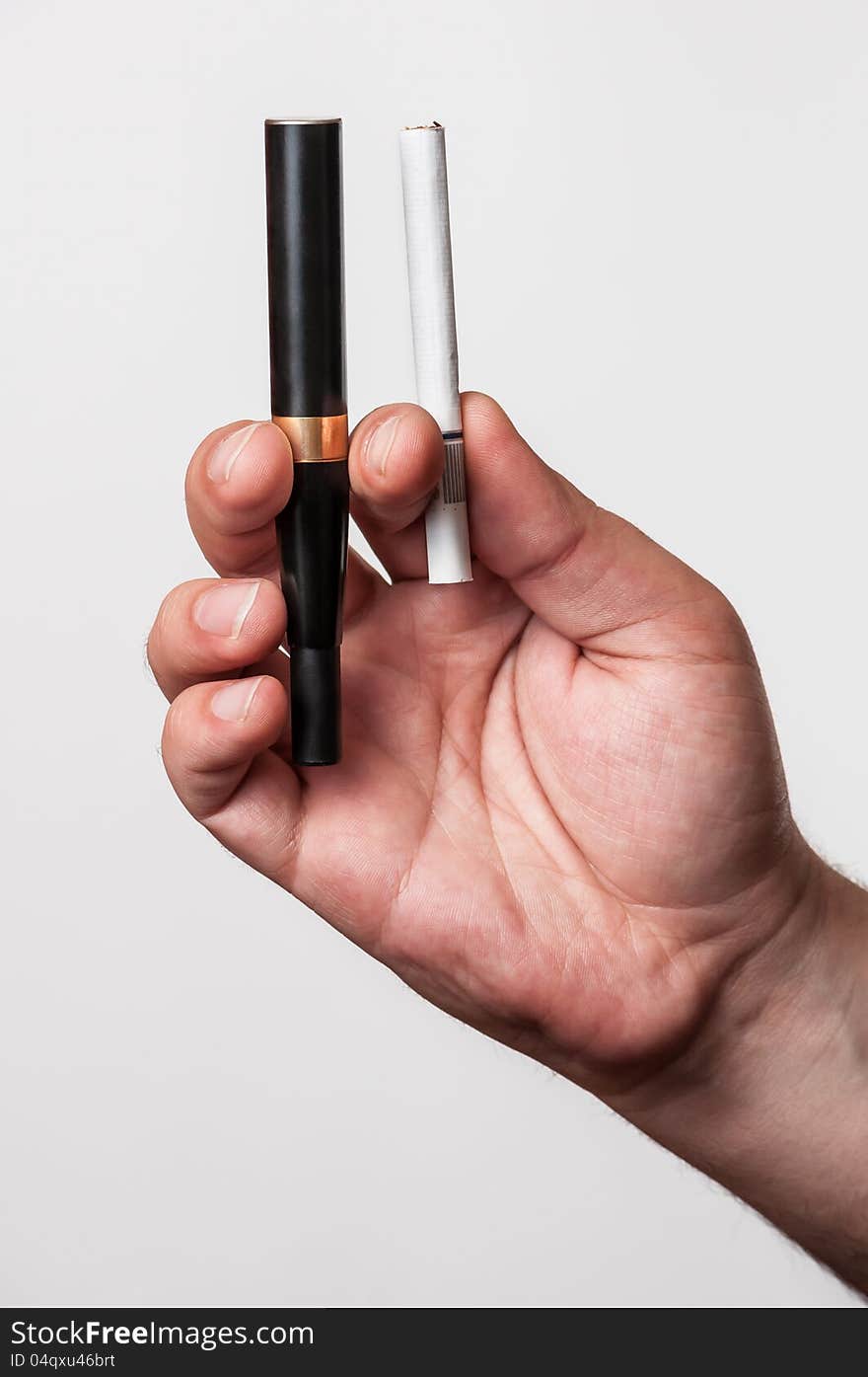 A black electronic cigarette and a real cigarette in a man's hand.