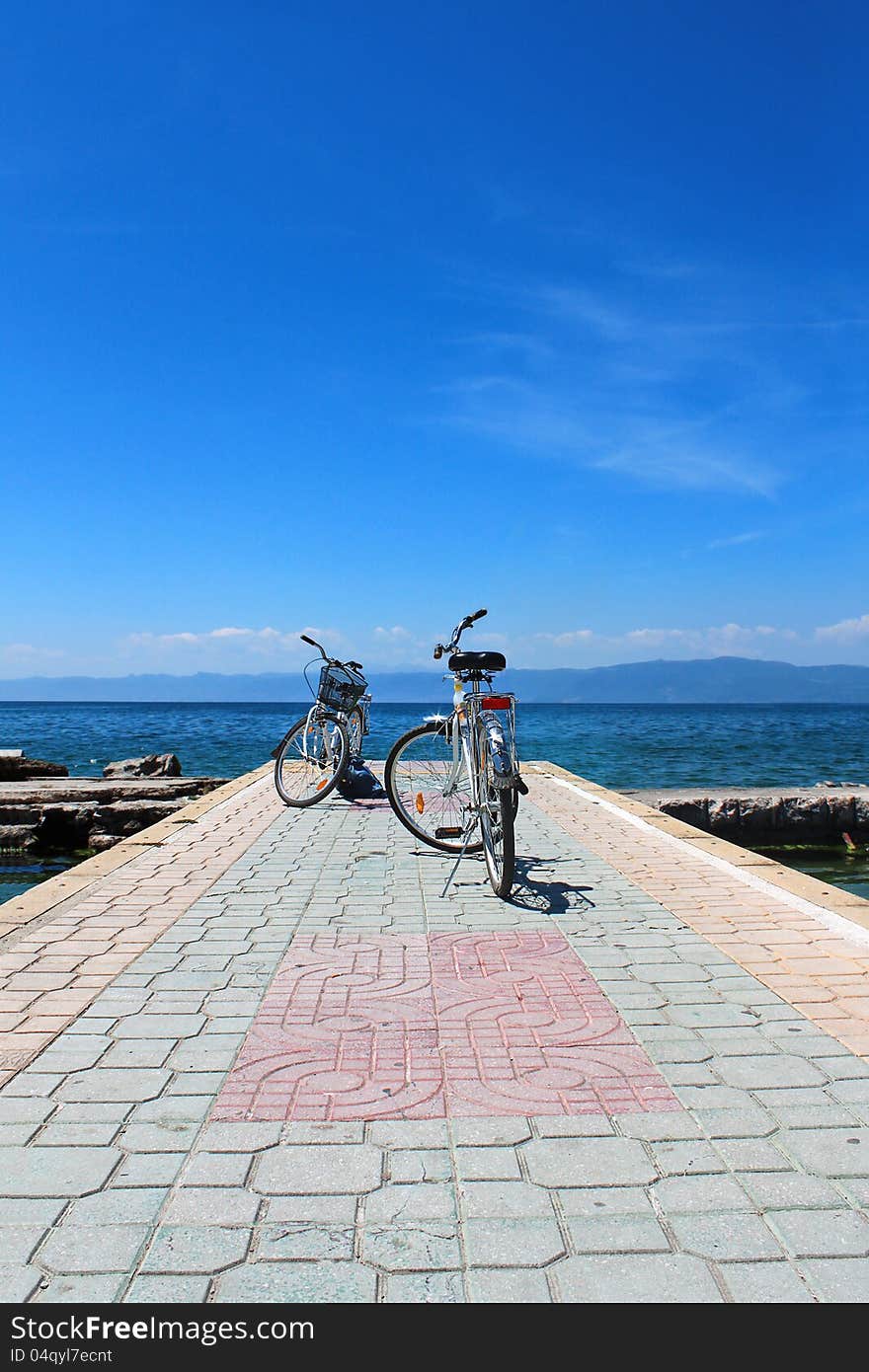 Two old, rusty, white bicycles with the lake Ohrid in the background,. Two old, rusty, white bicycles with the lake Ohrid in the background,