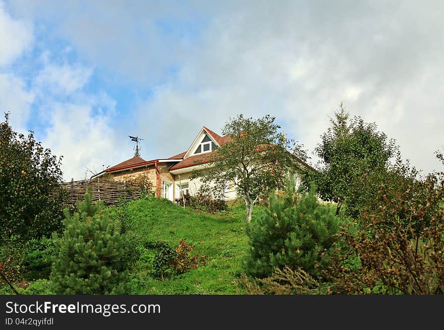 Residential house with red top among trees on the hillside. Residential house with red top among trees on the hillside