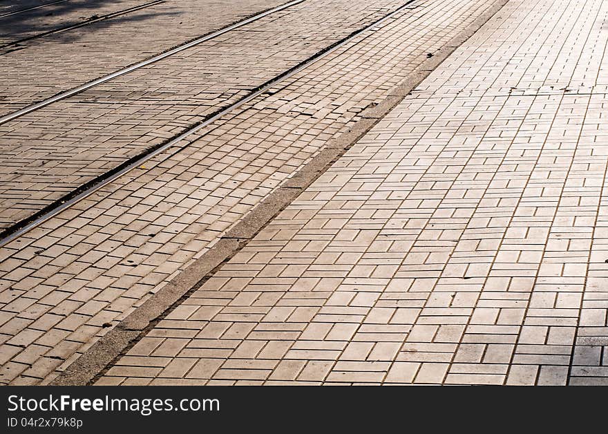 Cobblestone road in the sunlight with tram's rails