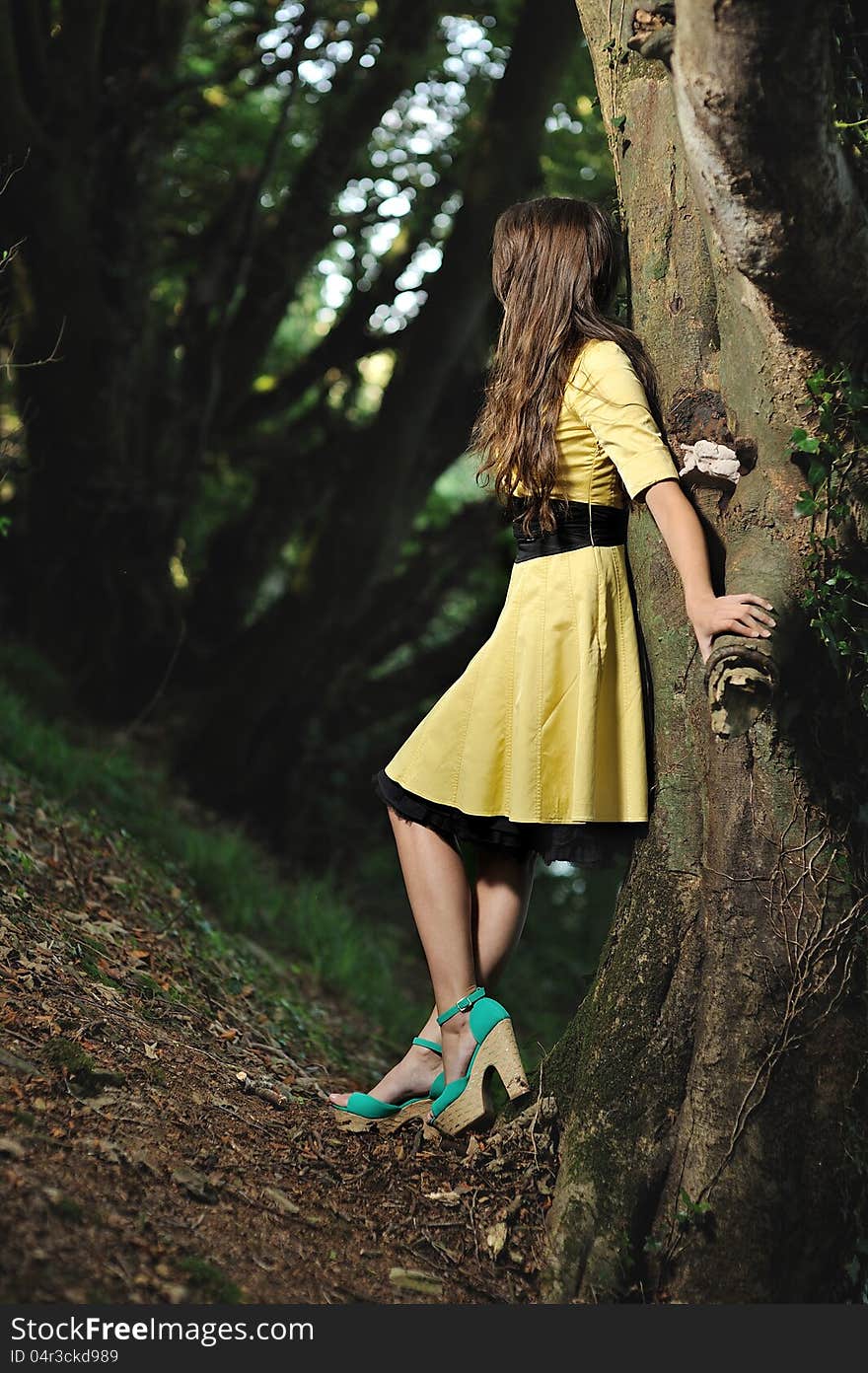 A Girl Leaning Against A Tree In A Forest.