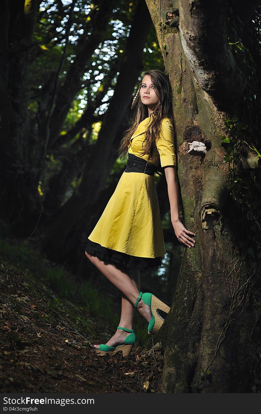 A girl leaning against a tree.