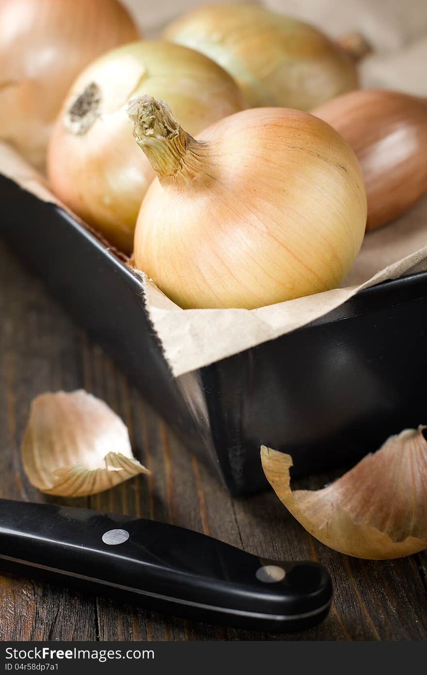 Onions close up in iron box on kitchen table