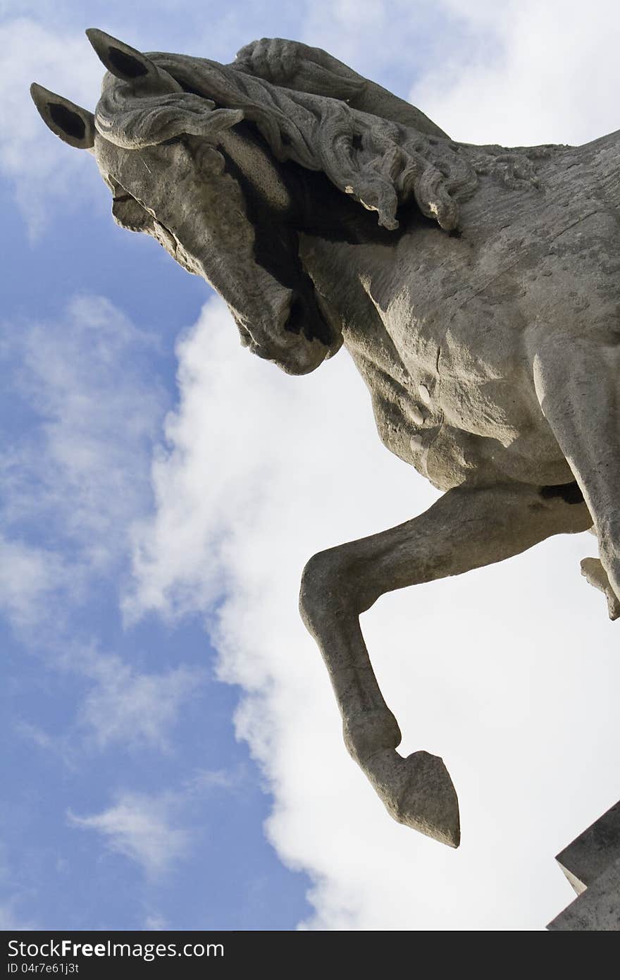 Close view of a stone horse statue over a cloudy blue sky.