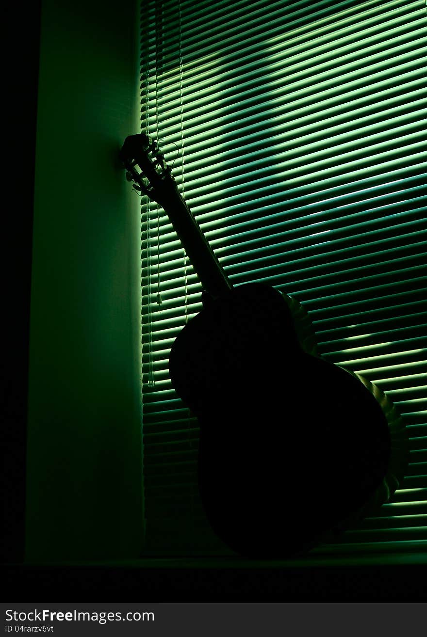 Acoustic guitar on a green background. Near the window