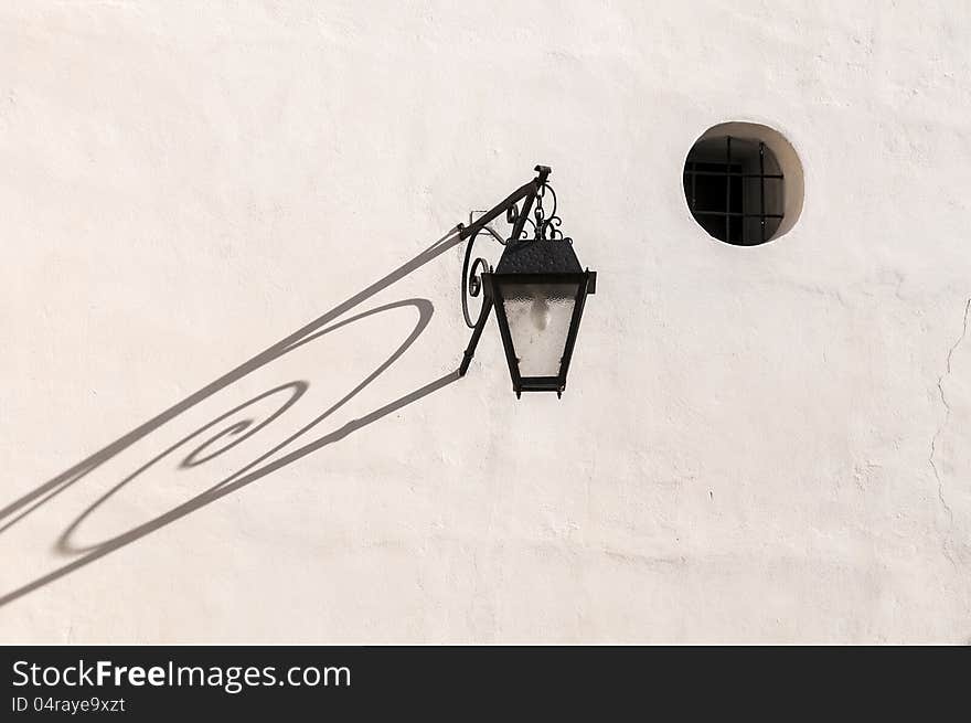 Old lantern on the white wall of a house