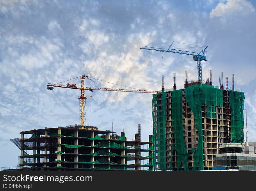 Building crane and building under construction against blue sky