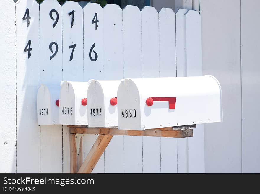 4 mailboxes in front of white fence