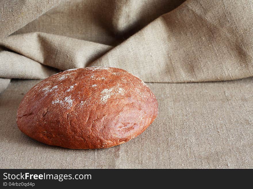 Round rye bread lying on canvas surface with free space for text