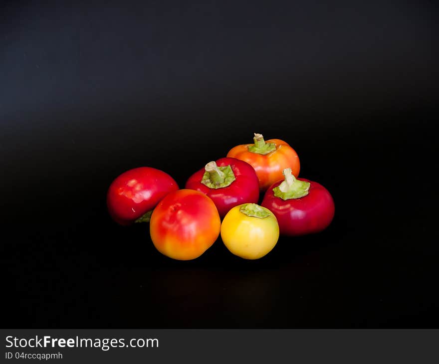 Round little colorful peppers on a black background. Round little colorful peppers on a black background