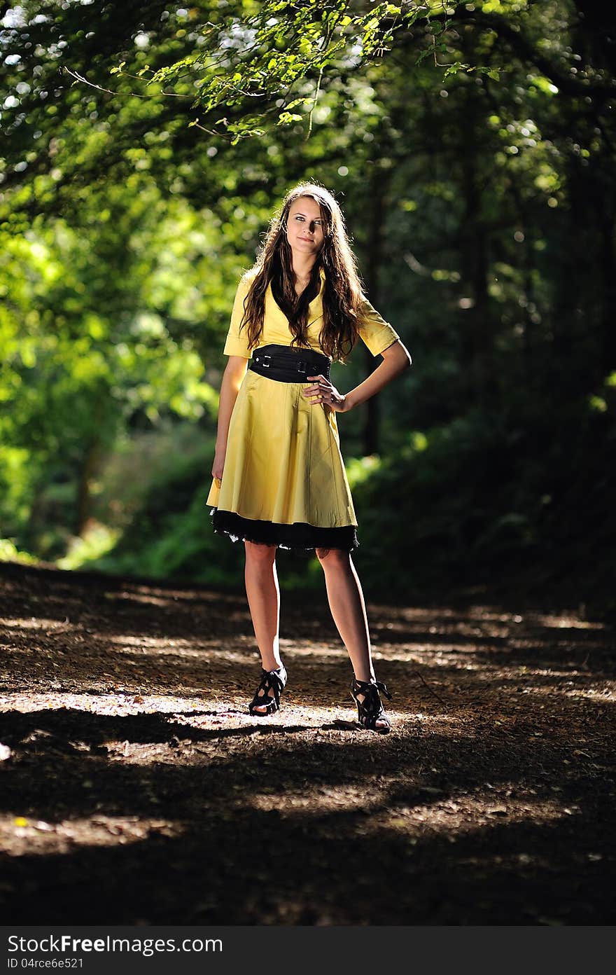 A girl in the forest surrounded by sunlight.