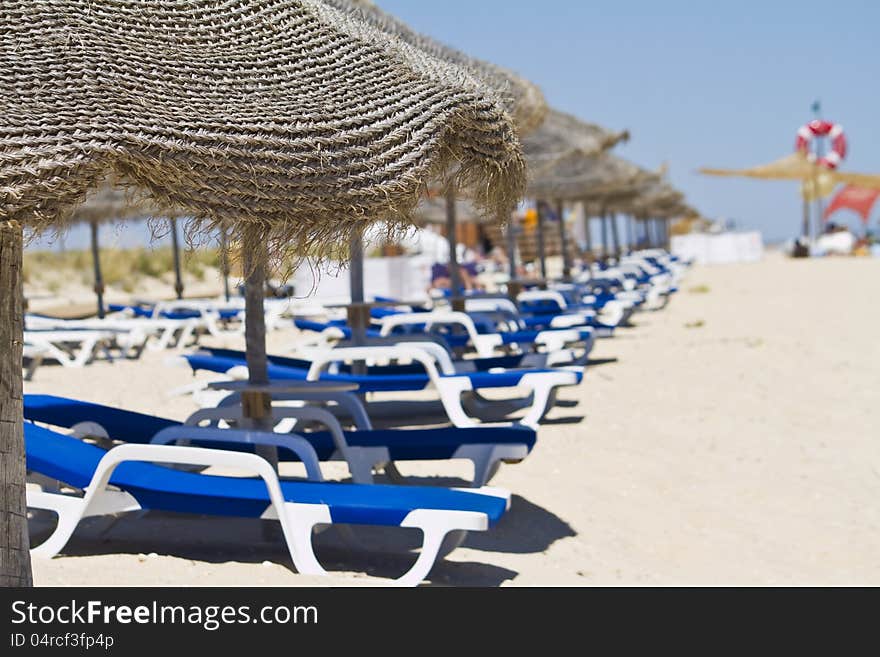 Beach chairs with straw umbrellas