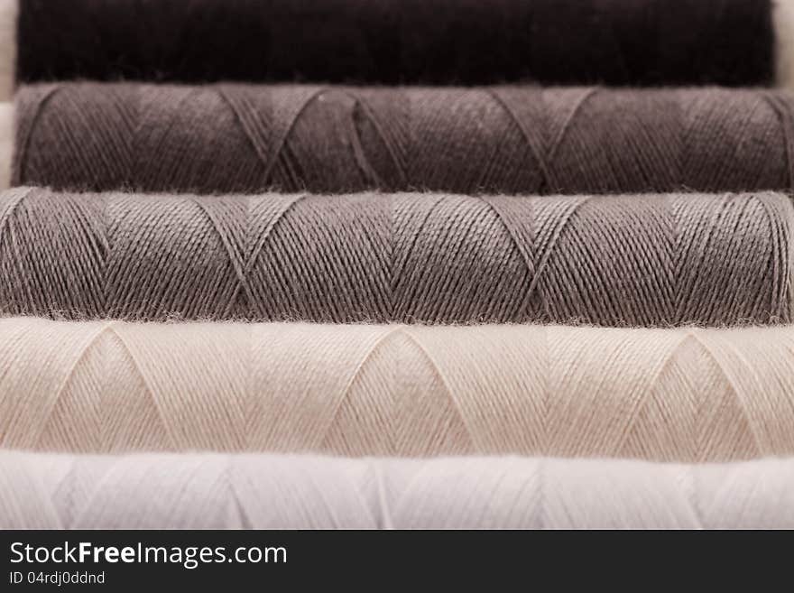 White, grey and black rolls of thread. Closeup, shallow depth of field. White, grey and black rolls of thread. Closeup, shallow depth of field.