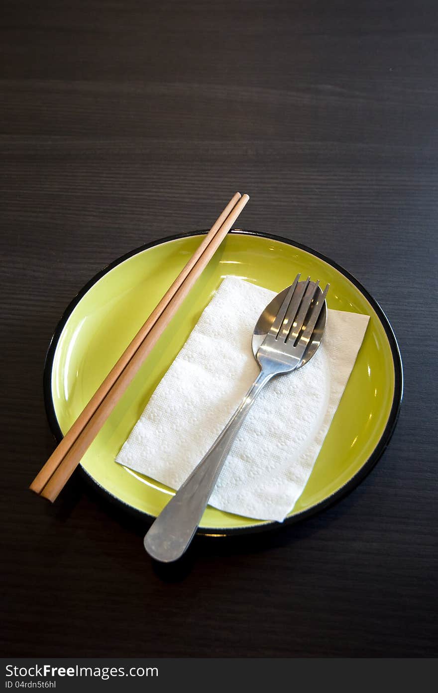 Dish set with chopsticks spoon fork napkin on green dish