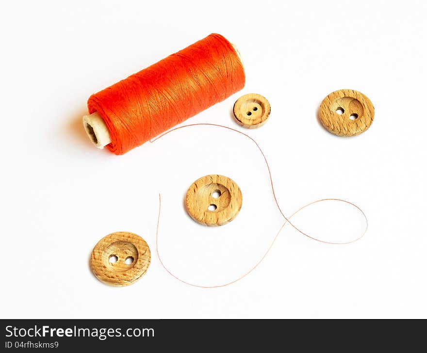 Spool of red thread and buttons on a white background. Spool of red thread and buttons on a white background.