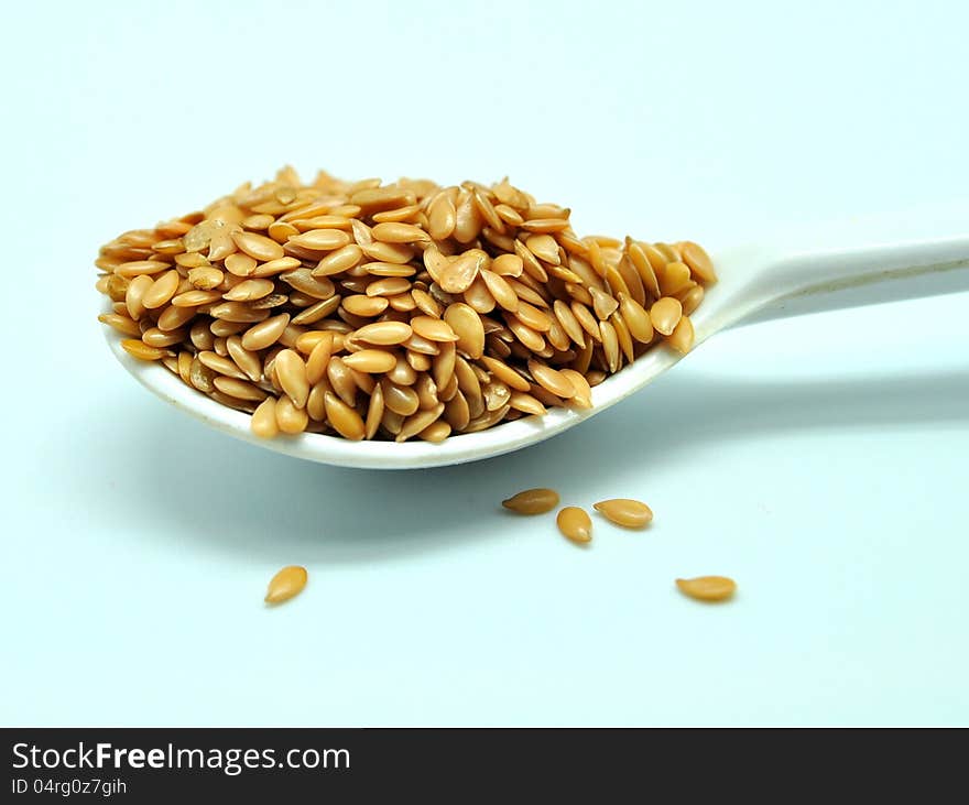 Golden flaxseed, displayed on a small white spoon. Flaxseed is great ingrediants for healthy foods.