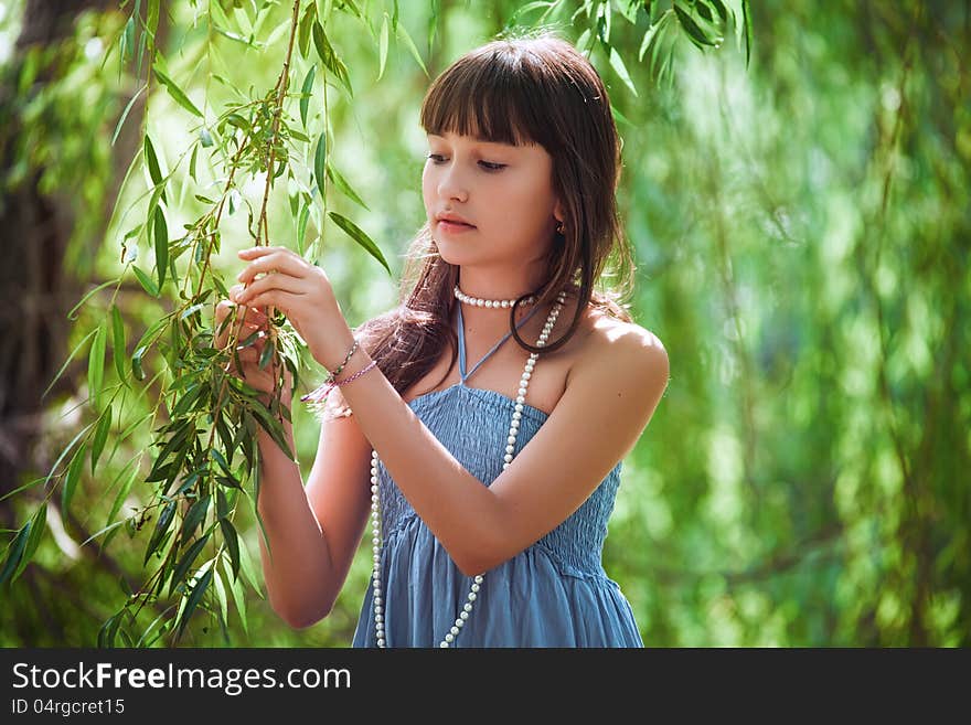 Girl in blue dress staying near a osier. Girl in blue dress staying near a osier