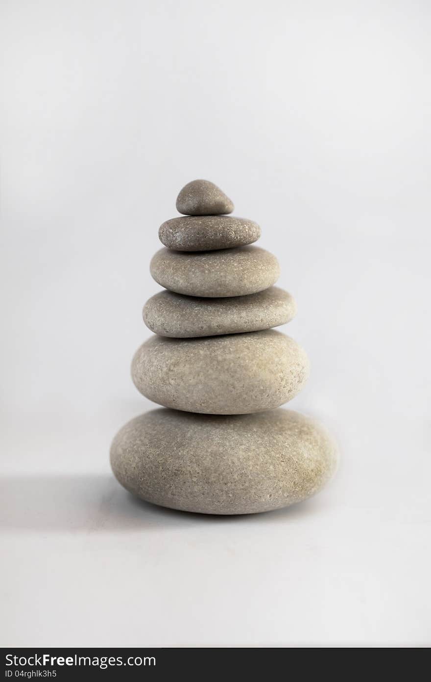 A zen tower arrangement of stones on white background. Symbol of inner peace, harmony and stability. A zen tower arrangement of stones on white background. Symbol of inner peace, harmony and stability.