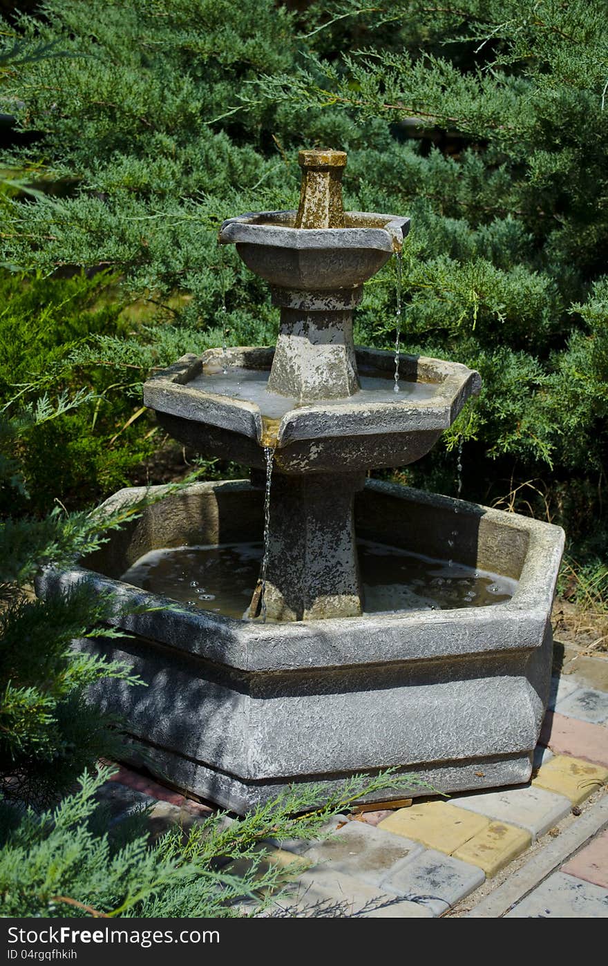 Fine stone fountain in park among trees