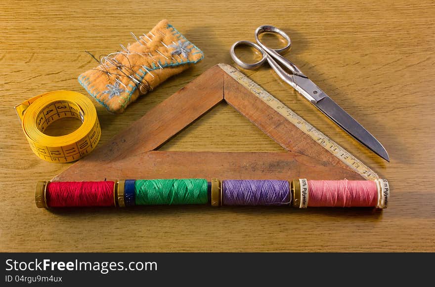 A few old sewing tools: pins, spools, scissors, tape and a wooden square ruler