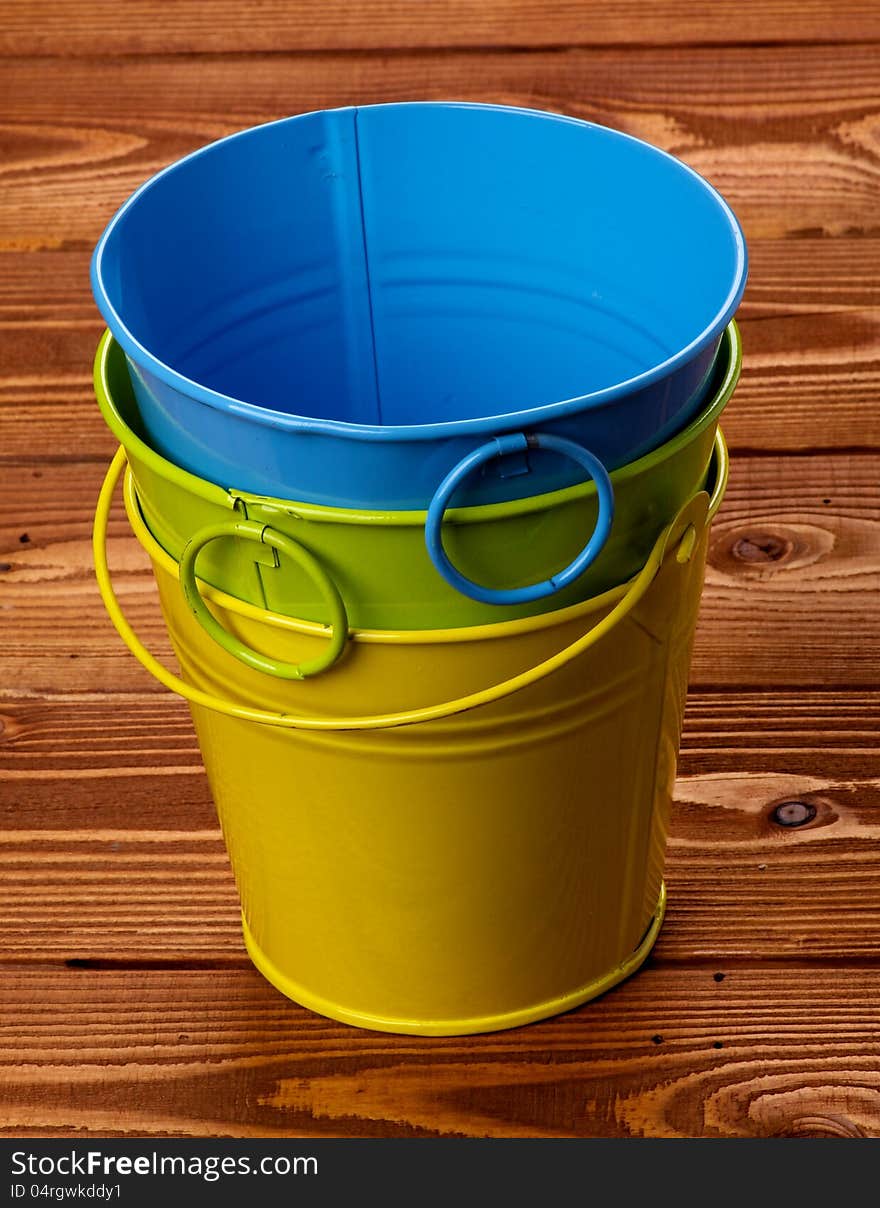 Stack of Three Colour Tin Buckets isolated on wooden background