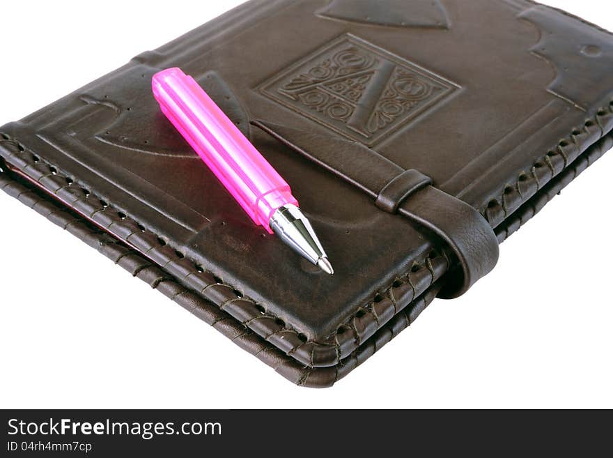 Pink pen lies on a notebook on a white background