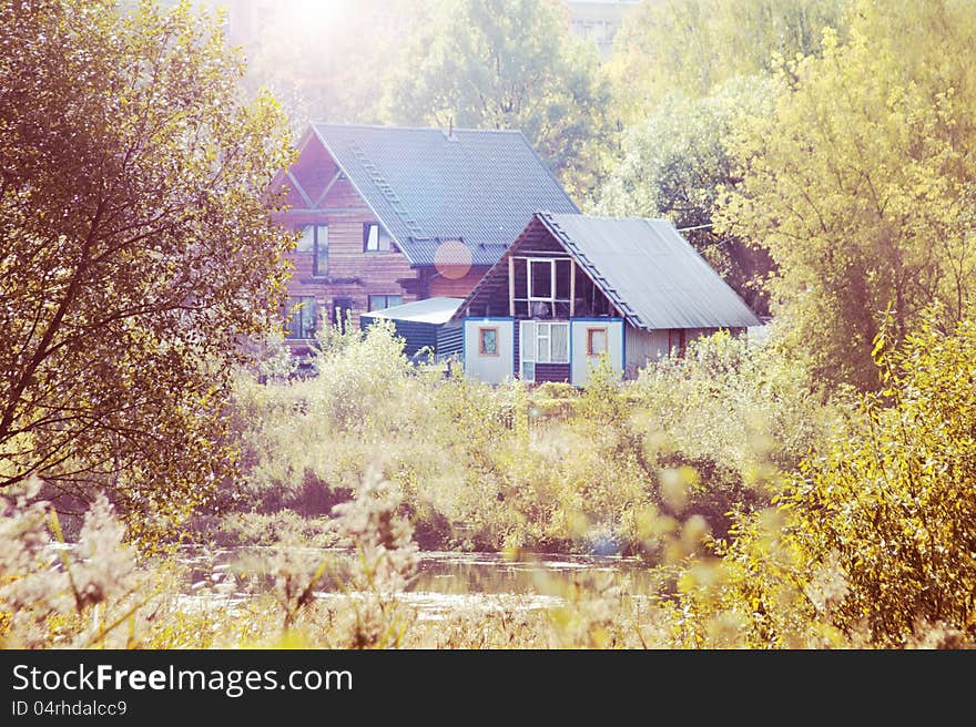 Two houses in the autumn forest on the bank of the river