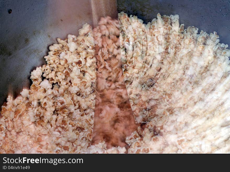 A farmer is making popcorn in a big container in a traditional way with lot of oil.