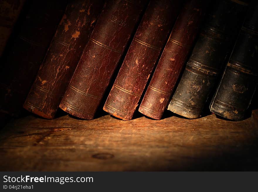 Stack of old books in a row on wooden surface