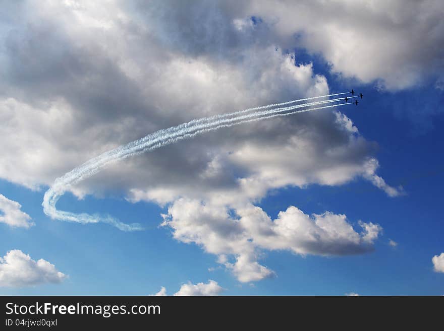 Four aircrafts living smoke trails in blue cloudy sky background