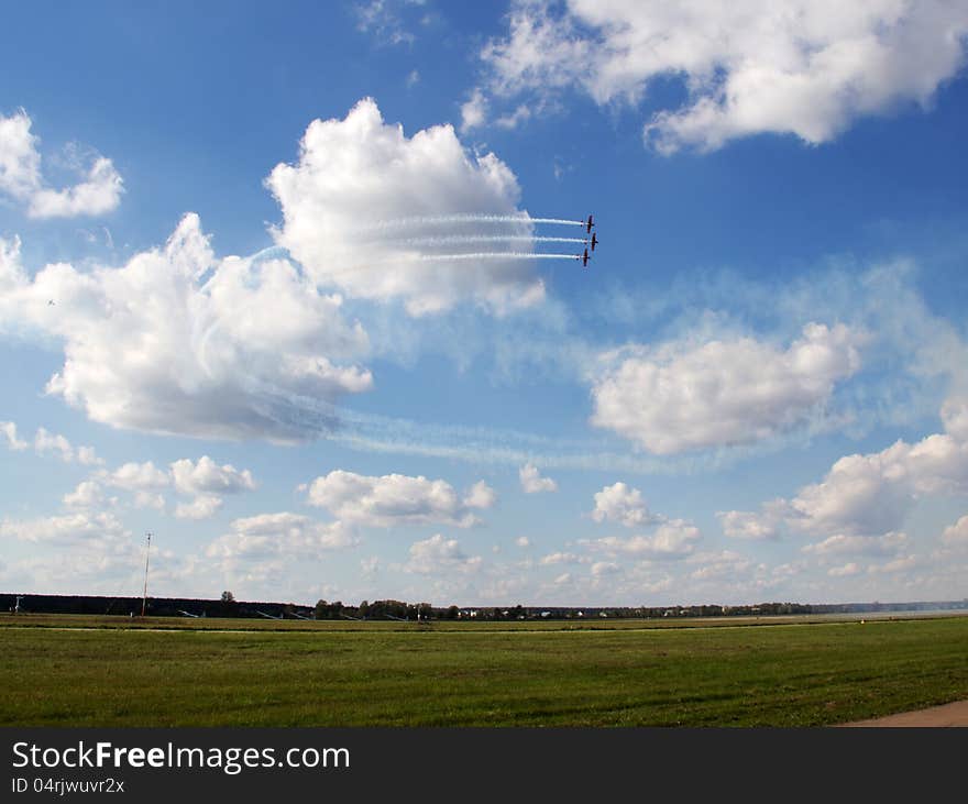 Three aerobatic planes flying in formation on blue cloudy sky background. Three aerobatic planes flying in formation on blue cloudy sky background