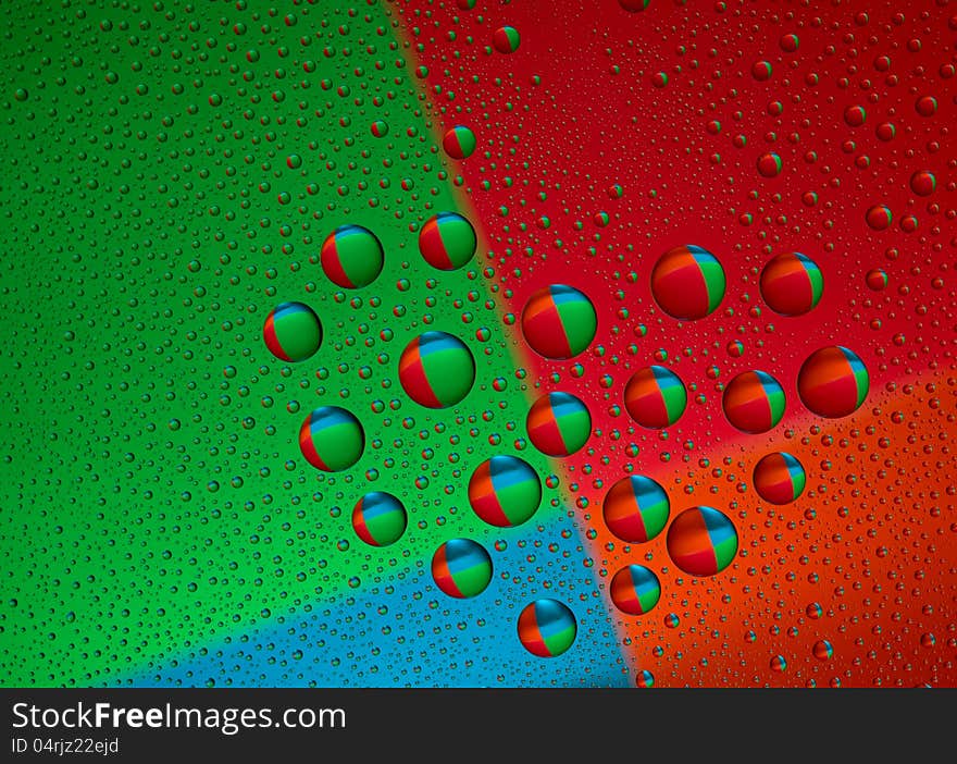 Drops of water on glass in a heart shaped. Colorful background is reflected in the drops. macro. Drops of water on glass in a heart shaped. Colorful background is reflected in the drops. macro