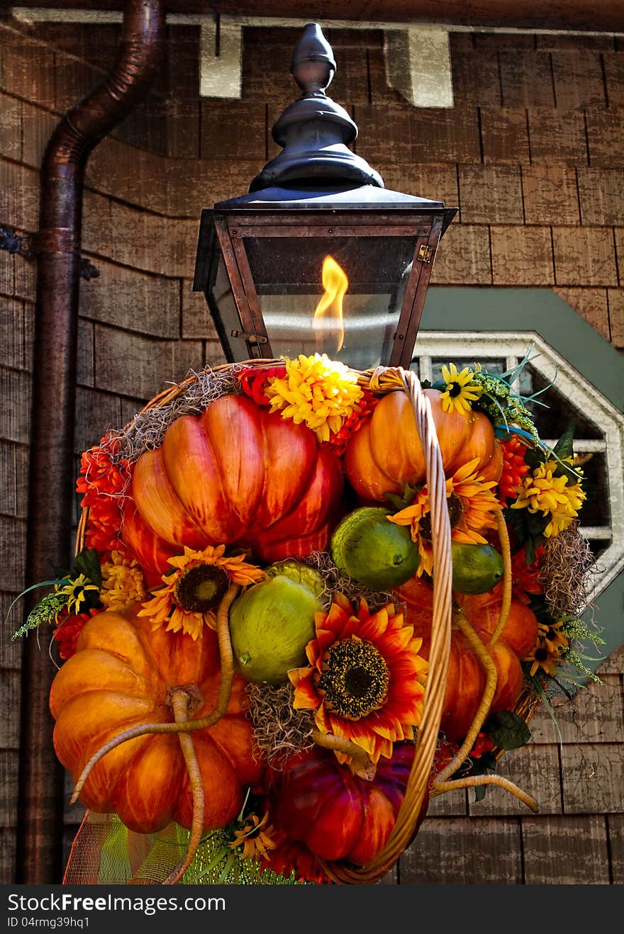 Fall Decoration on rustic lamp with flame and rustic building in back ground.