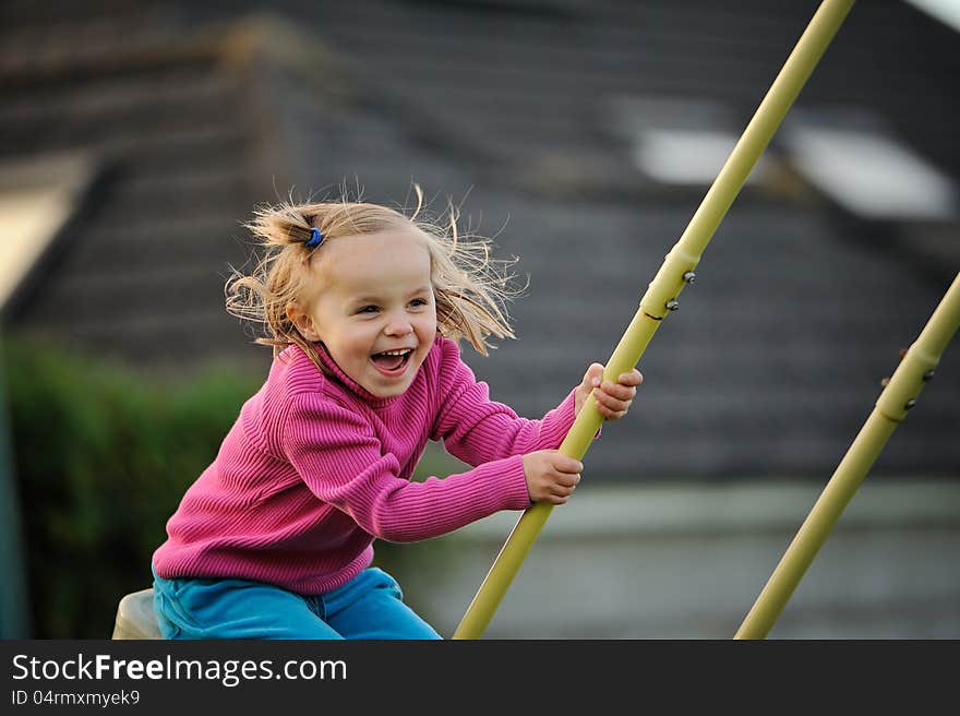 A young girl laughing on the swings. A young girl laughing on the swings.