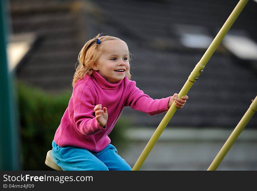 A happy child on swings, enjoying herself.