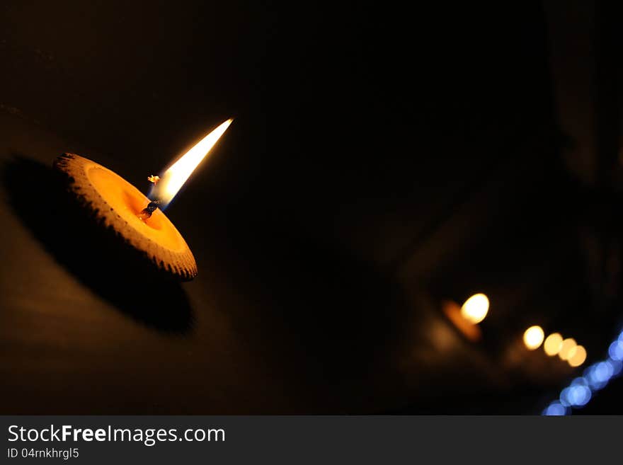 Line of burning candles on black background.