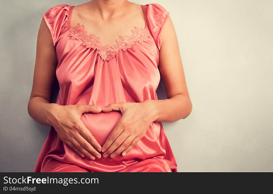 Pregnant woman doing yoga over light gray background