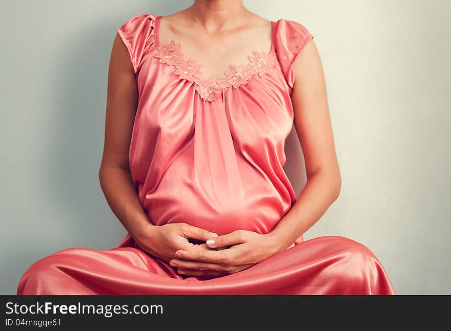 Pregnant woman doing yoga over light gray background