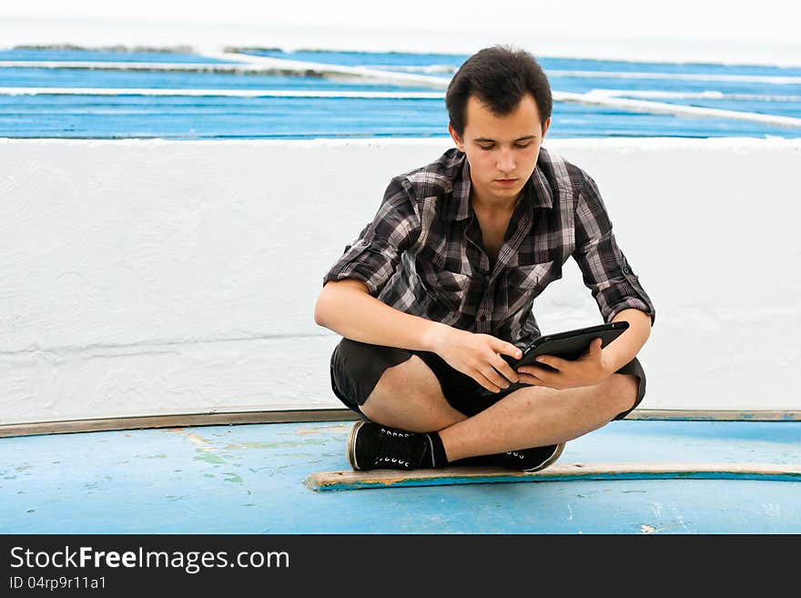 Young man sit on the board and work on the flatbed computer. Young man sit on the board and work on the flatbed computer