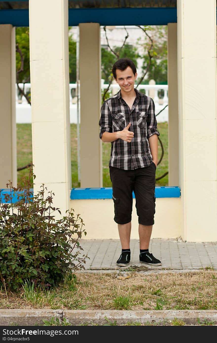 Young man stay near the pillar and had show big finger up