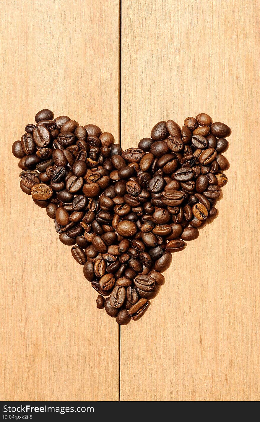 Heart shape coffee bean shot on the wooden background